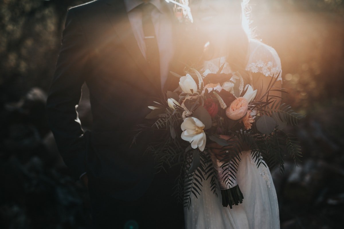 Couple holding a wedding bouquet in soft light